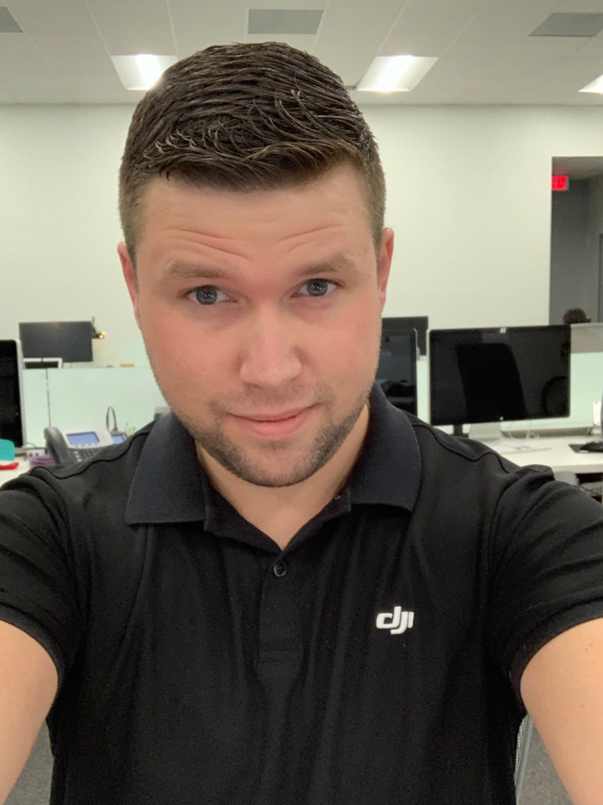 Jeremy Gulley in a black DJI polo shirt in an open-plan office