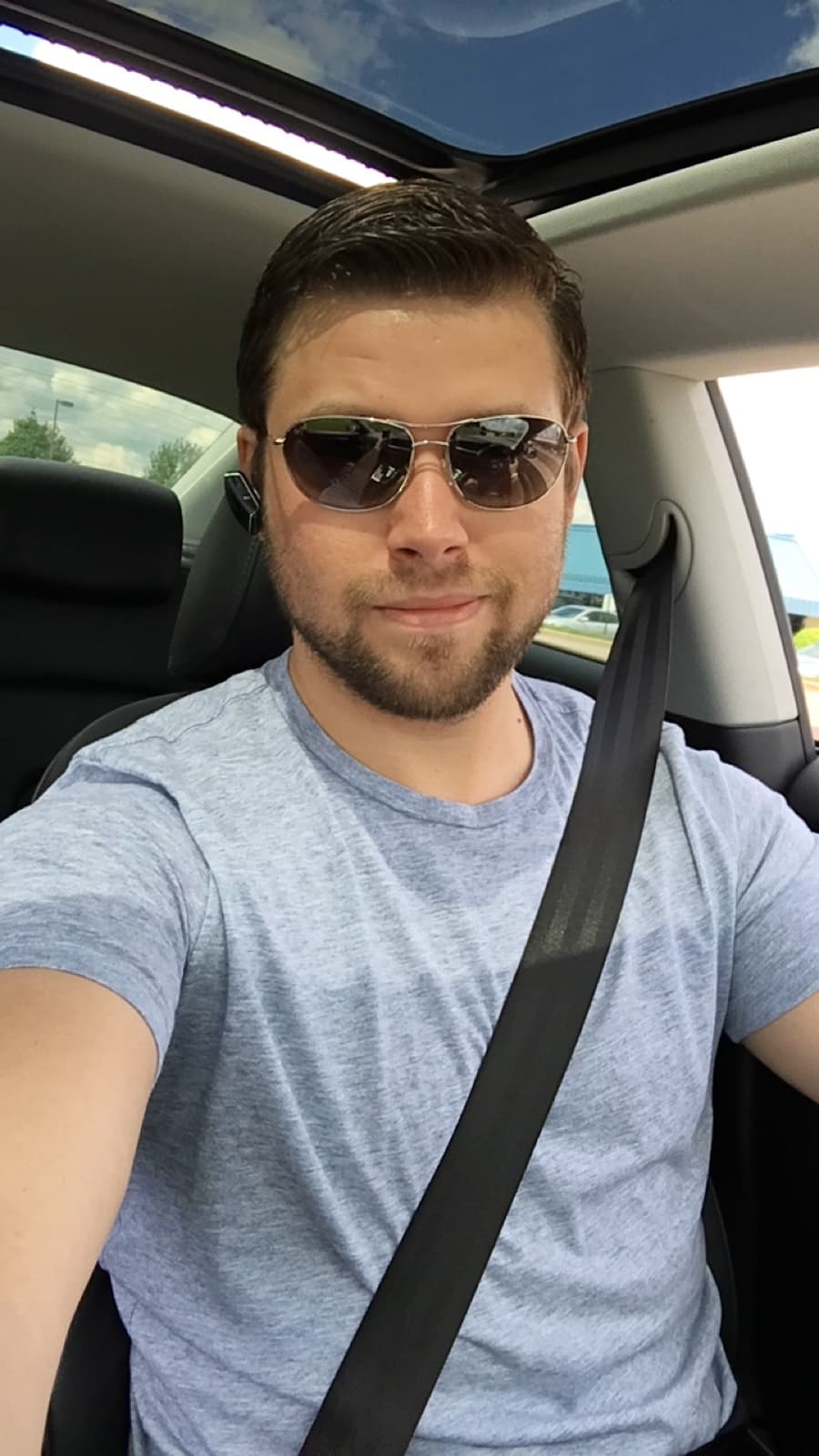 Jeremy Gulley in a grey t-shirt and sunglasses in the driver's seat of a car
